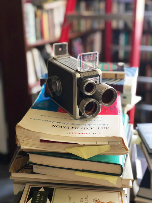 An old camera sitting on a stack of books.