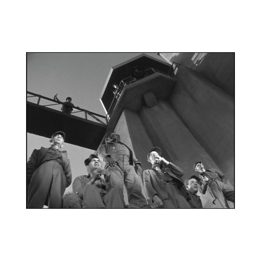 Black and white film still of men in a prison yard